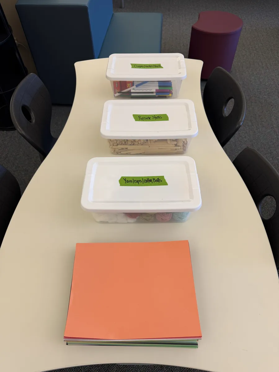 A row of labeled supply bins and a stack of colored paper