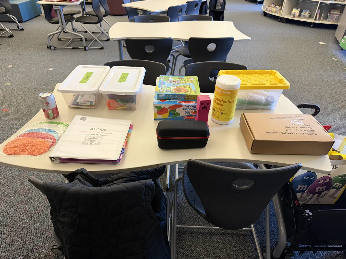 The day's supplies laid out on a table: bins, a binder, colored paper, and craft kits